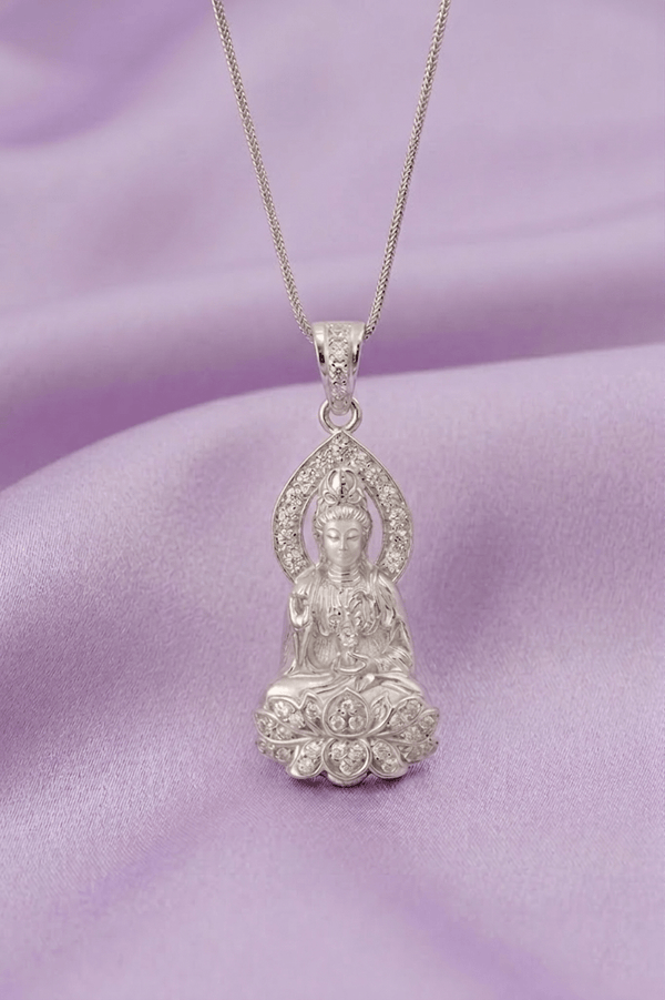 Silver Buddha pendant necklace on a purple fabric background